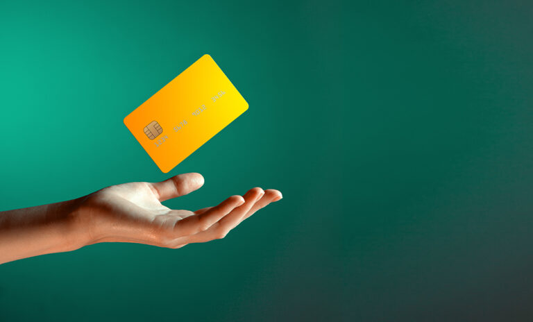 Hand reaching out with a yellow credit card floating above it on a green background