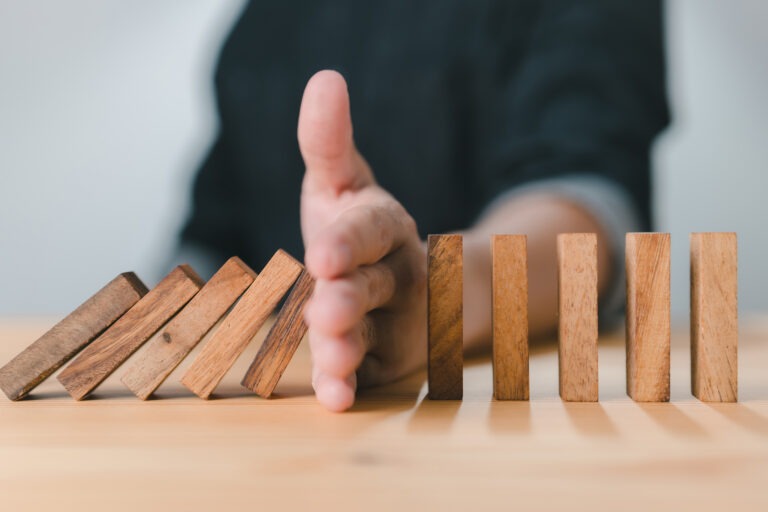 Man stopping domino blocks from falling