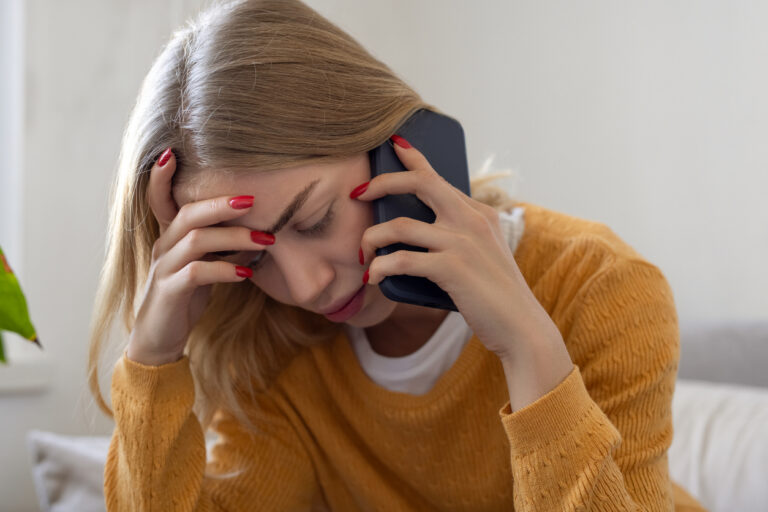 Woman looking stressed while talking to debt collector on phone