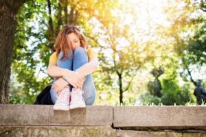 Woman sitting on concrete curb looking depressed