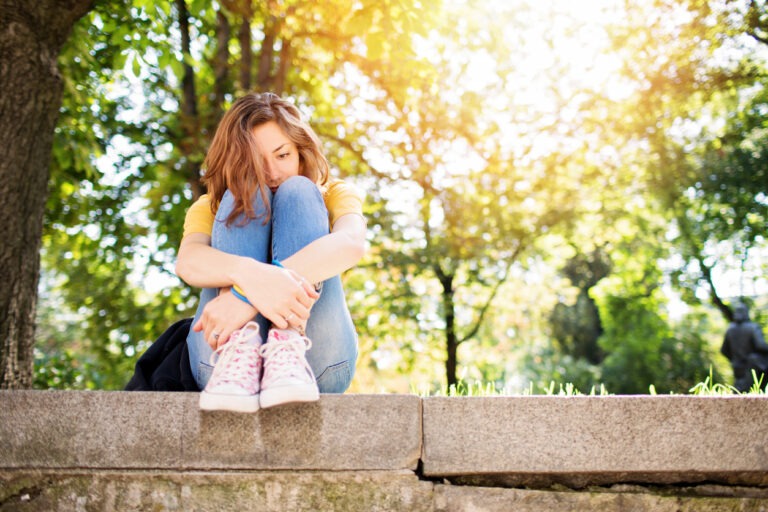 Woman sitting on concrete curb looking depressed