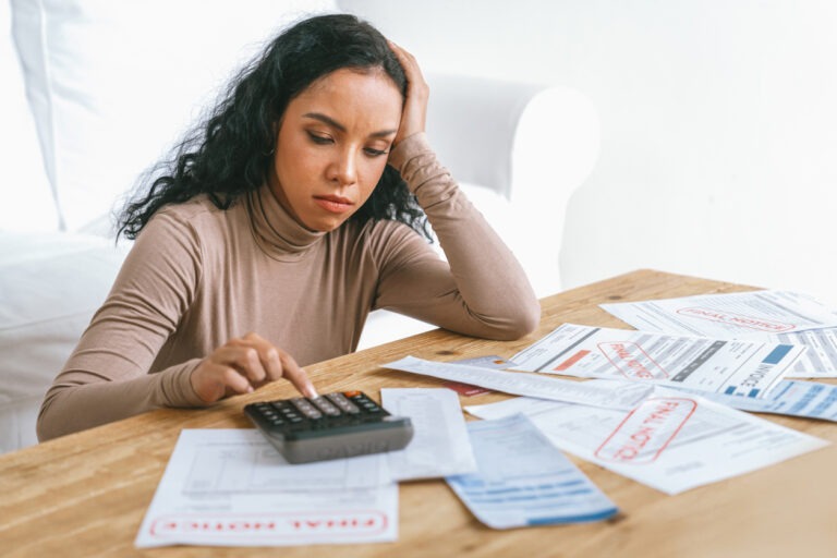 Stressed young woman looking at debt collection notices