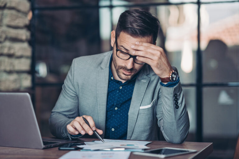 Man calculating bad debt expense at desk in suit