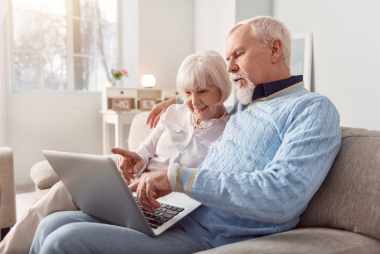 Senior couple looking at computer on couch