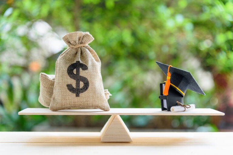 Bag of money on scale across from graduation cap