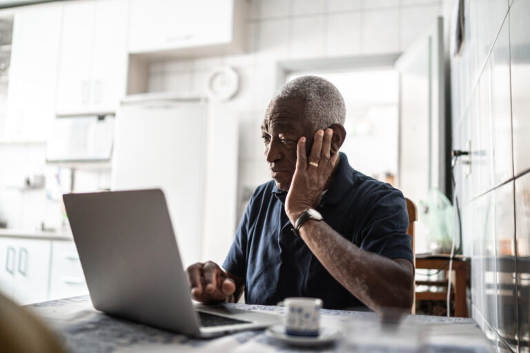 Senior man worried about debt working at laptop