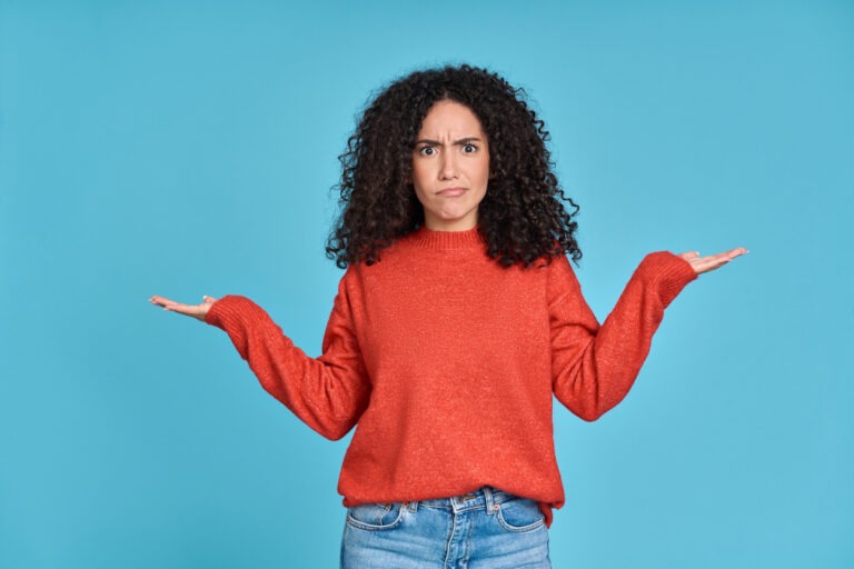 Young woman confused. Wearing red shirt with blue background