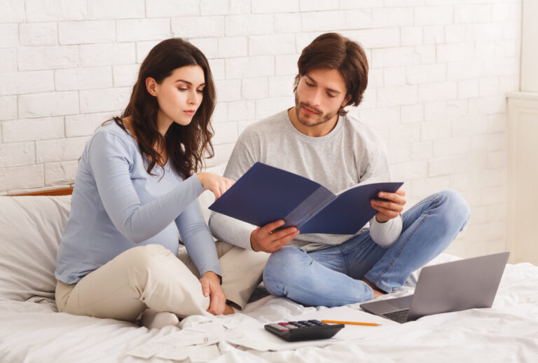 Couple looking over life insurance options on bed