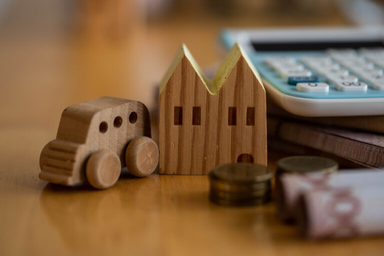 Installment debt. Wooden car and house next to coins and calculator