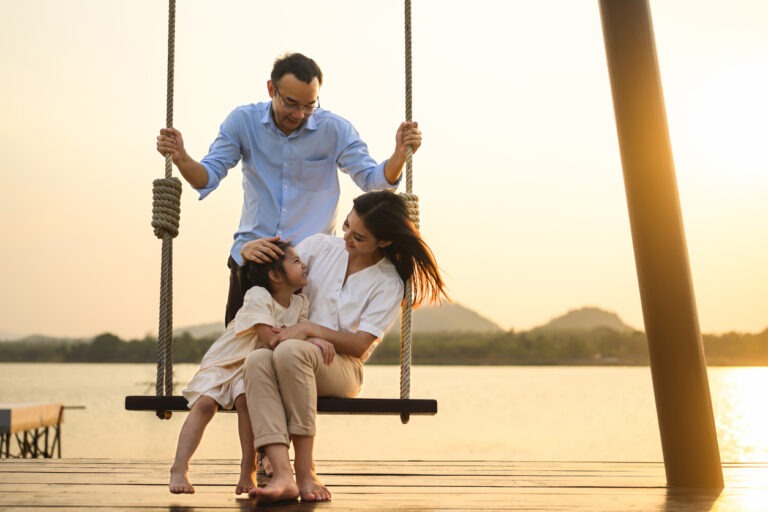 Family enjoying with outdoor activities sitting on swing with sunset on vacation.