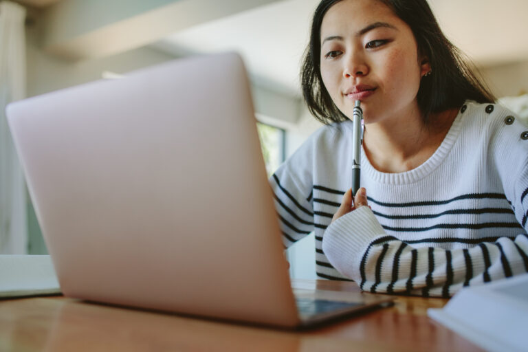 Woman on laptop at table looking at car insurance options