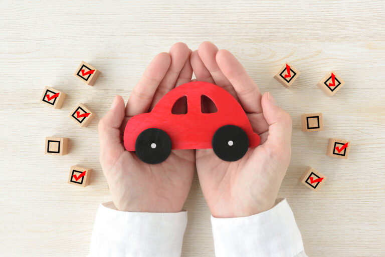 Car toy covered by human's hands surrounded by wooden blocks with checking marks