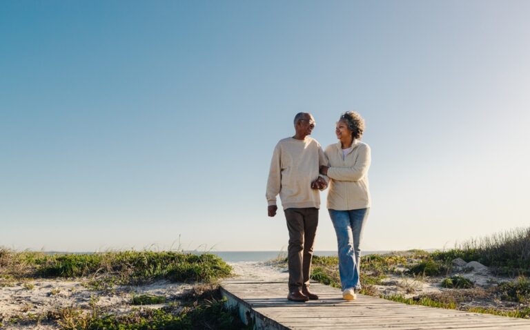 Senior couple walking on wooden beach path