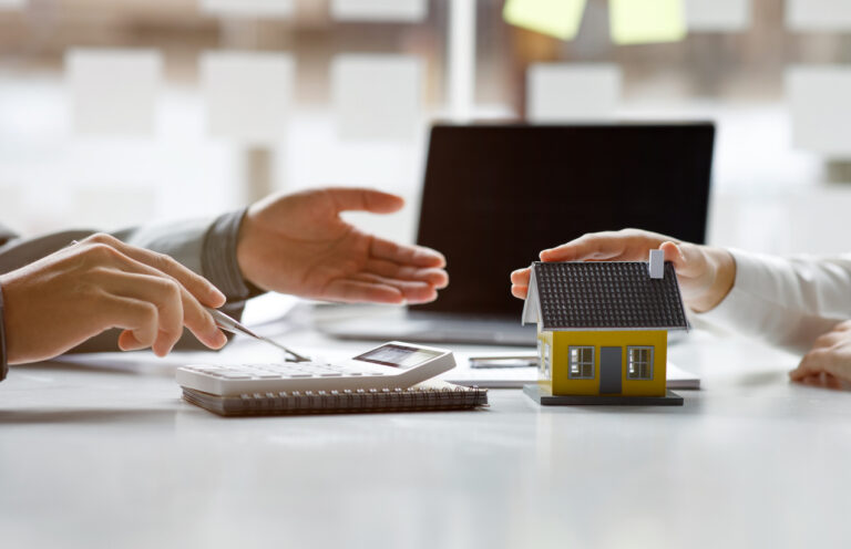 Man refinancing a home equity loan. Calculator and model home on table.