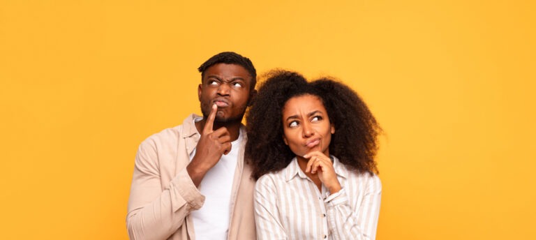 Pensive black couple in casual wear on yellow backdrop